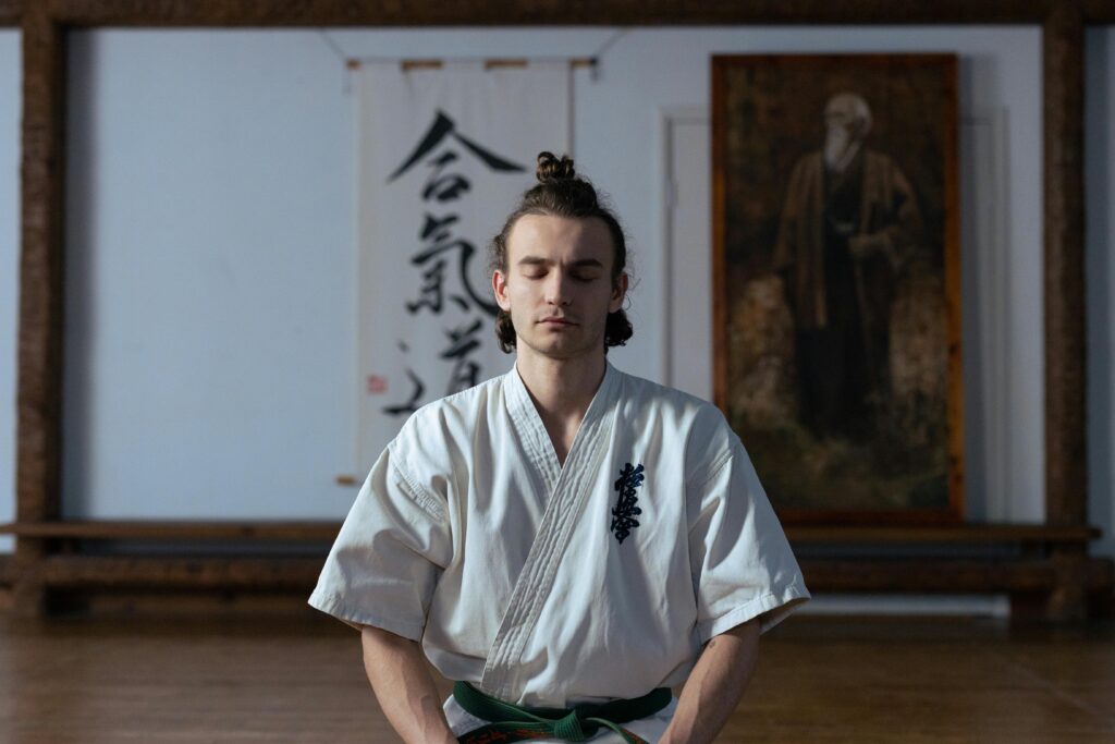 Martial artist meditating with eyes closed in a serene dojo environment.