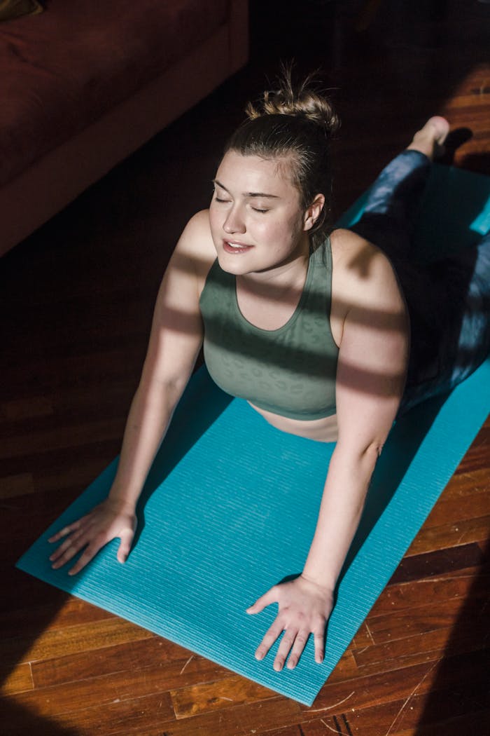 services-01 Woman performing a yoga stretch on a mat indoors with sunlight streaming in, creating a serene mood.